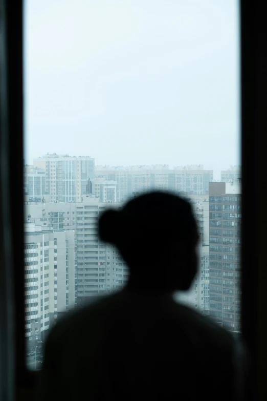 a person looking out a window at a city in the distance