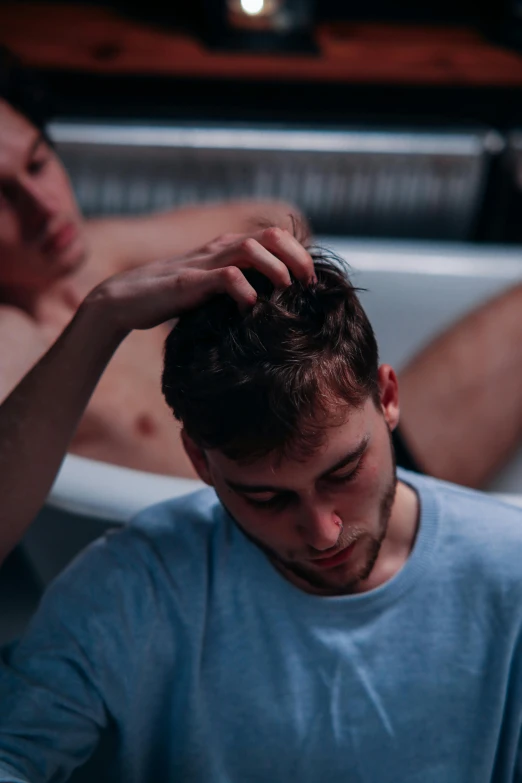 two people sitting in a bathtub with one touching his head