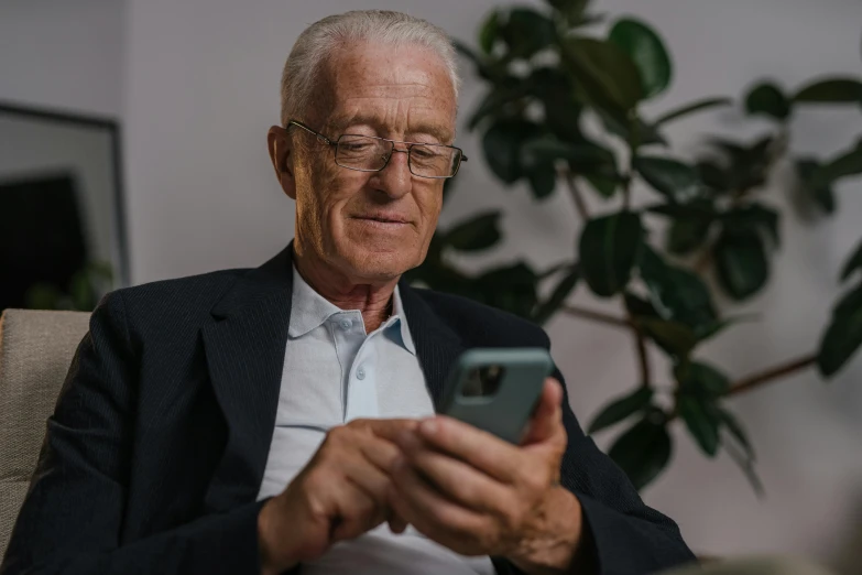 a older man using his cell phone while sitting down