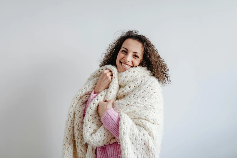 a woman is smiling while wearing a white scarf