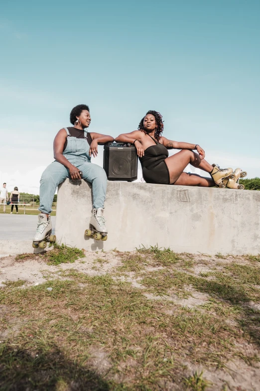 two women sit on the ledge while they are dressed in  clothing