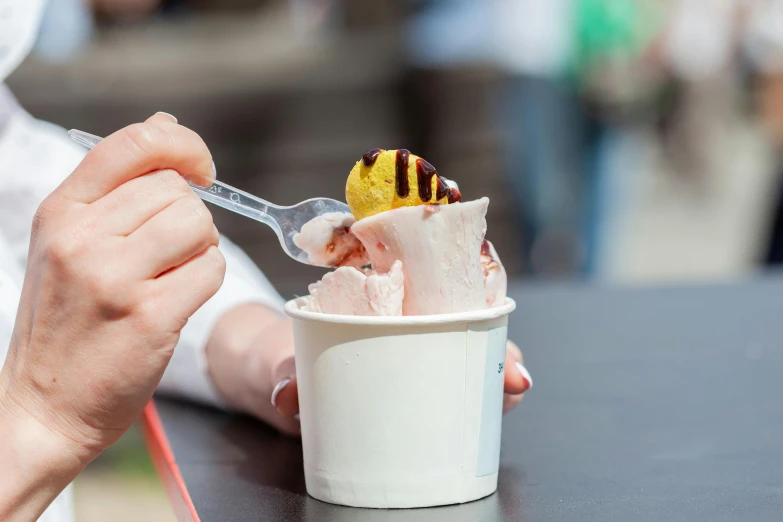 the person is eating a desert in a paper cup