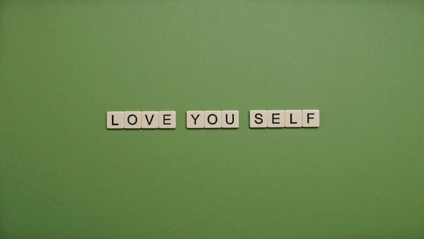 the words love you self spelled with scrabbles on a green wall