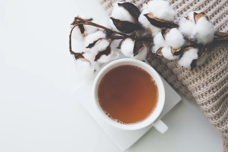 a cup of tea sitting next to cotton floss