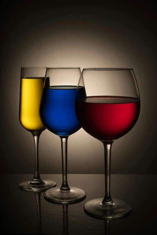 three glasses with different colored liquids and one empty