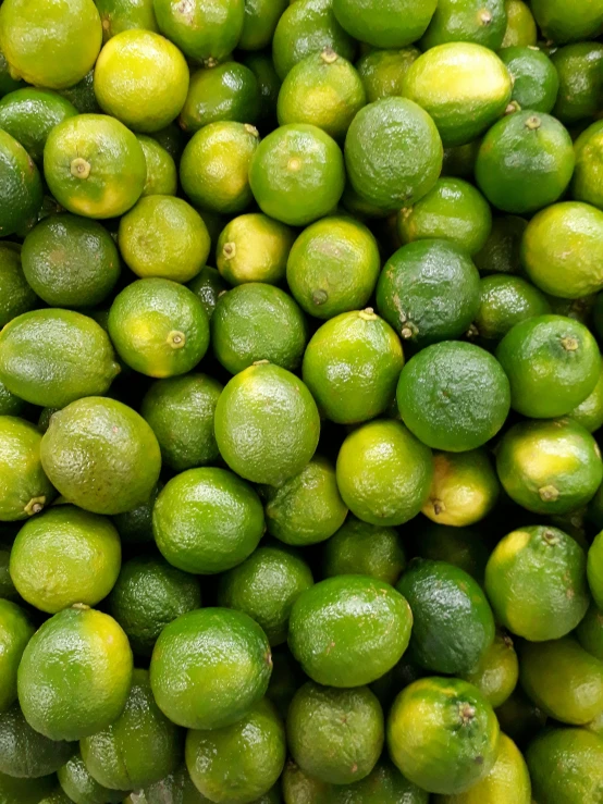 a large bunch of limes and a bundle of limes sitting on display