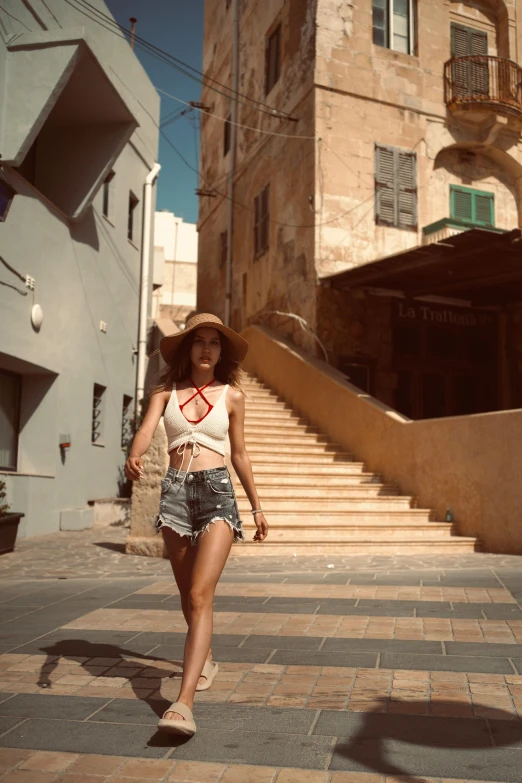 a young lady with a straw hat is walking down the street