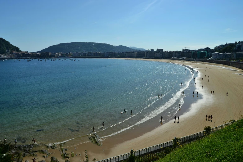 the shoreline of the ocean has many people walking in it