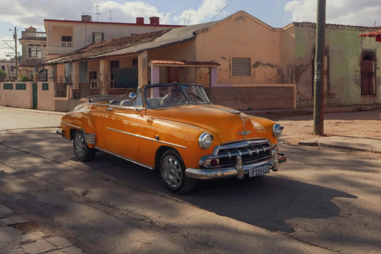 a yellow old style convertible car parked in front of a building