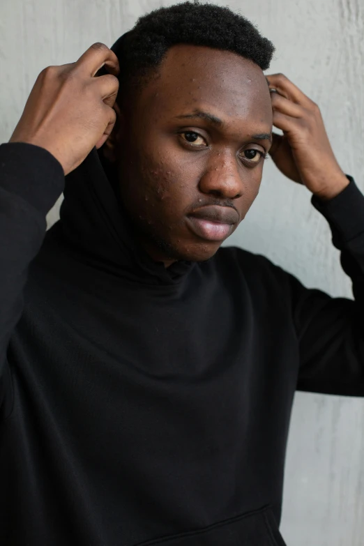 a man wearing a black shirt is fixing his hair