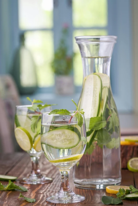 a pitcher and two goblets with sliced cucumbers