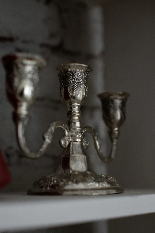 a couple of silver candles sitting on top of a mantle