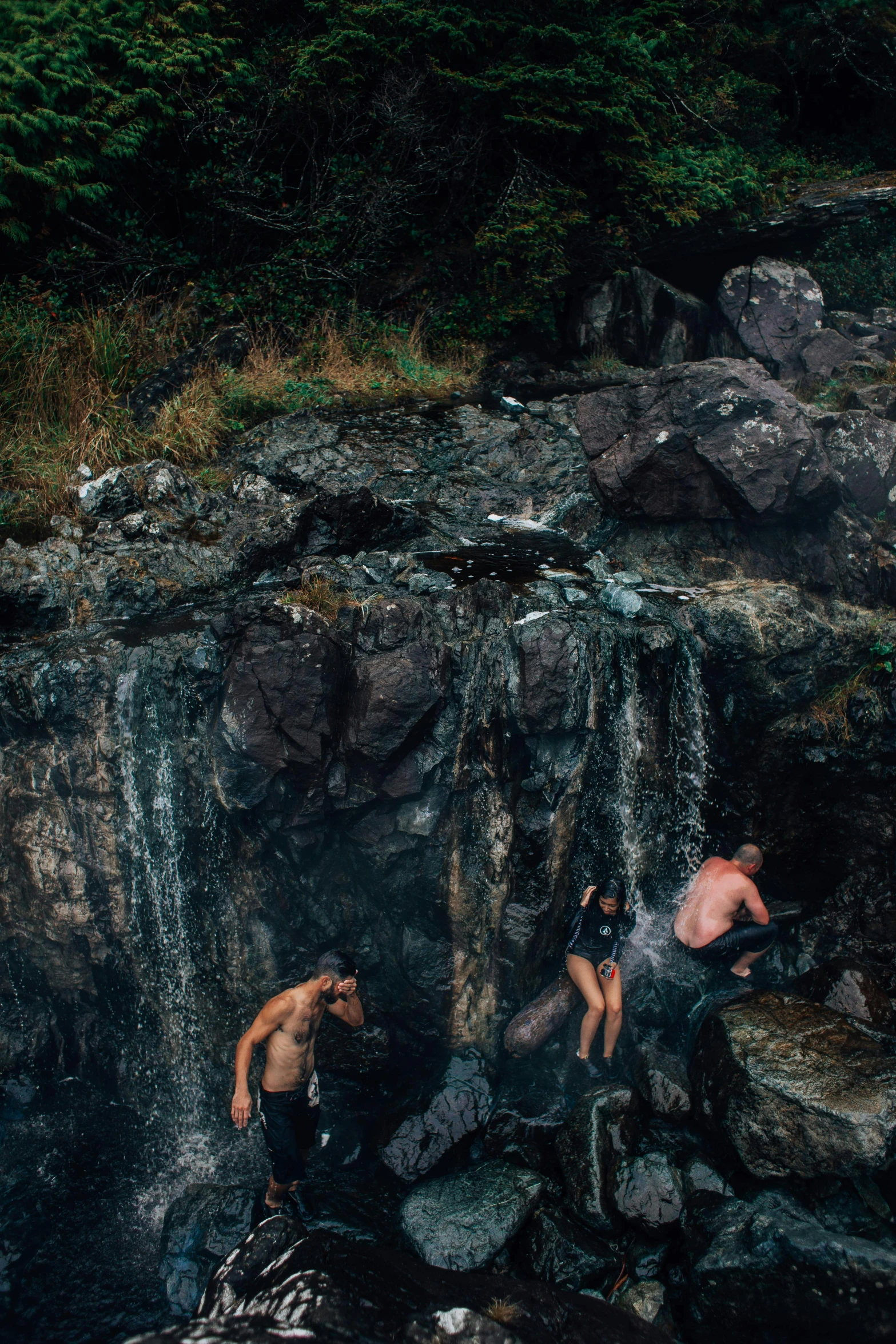 three people hanging out at the base of a waterfall