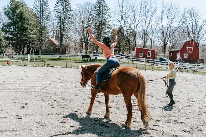 a woman on a horse waving to someone else