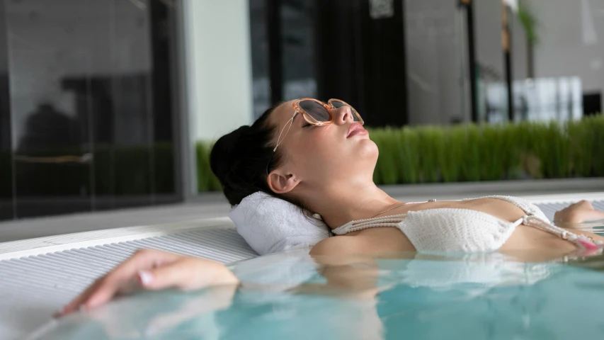 a woman lies next to the pool in the sun