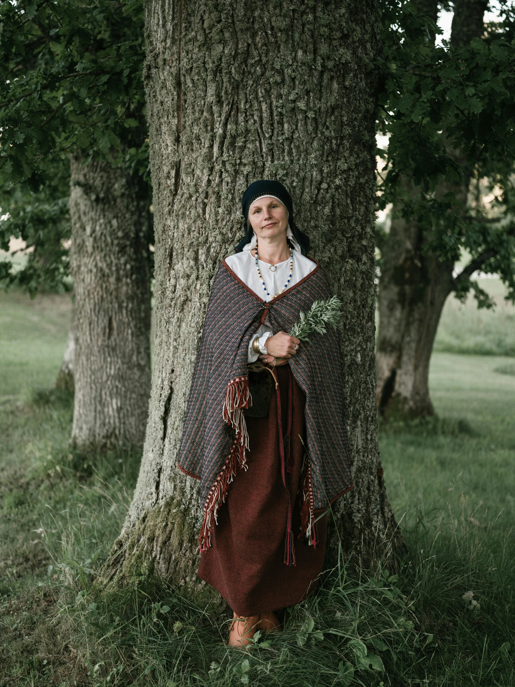 a woman poses in the grass between two trees