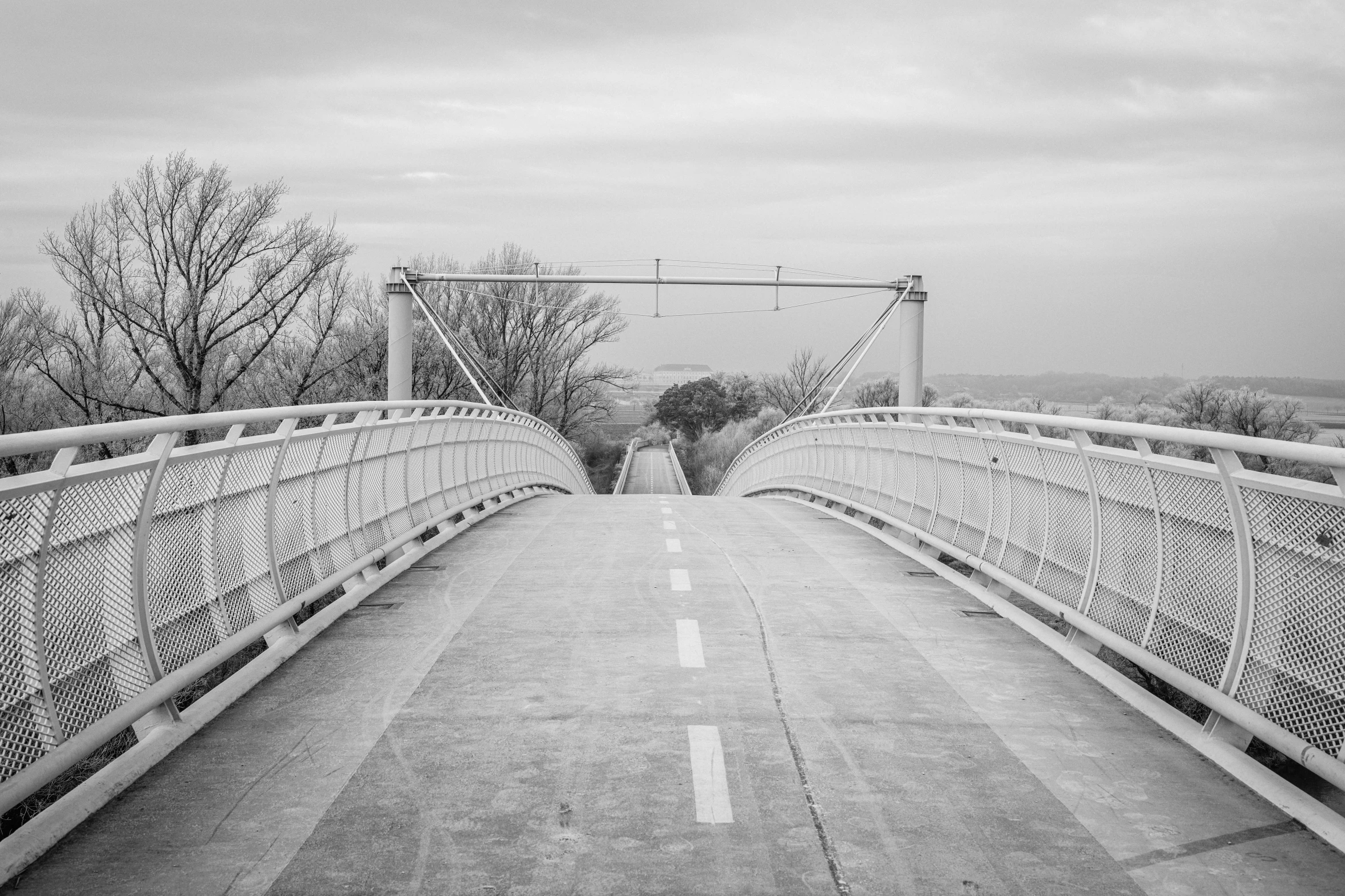 an old metal bridge crosses the river into the distance