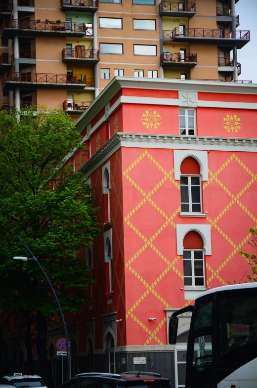 there is a large pink and yellow building next to the street