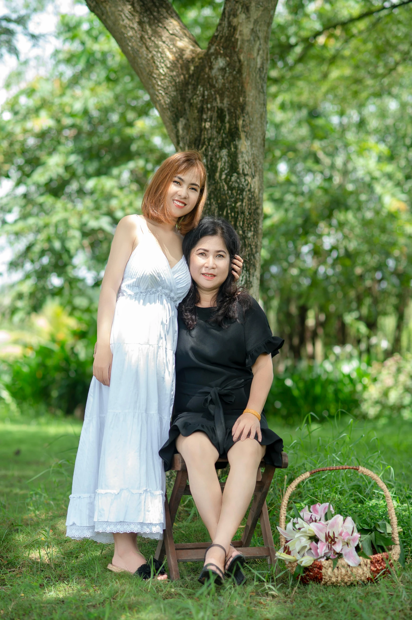 two beautiful young ladies pose for the camera in a park