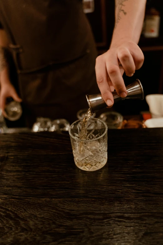 a bar attendant pours a drink into a tall glass