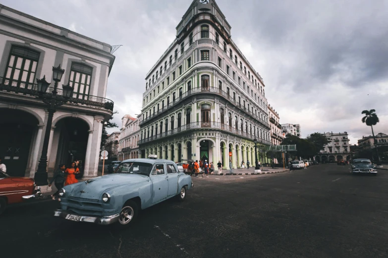 an old blue car is parked in front of a white building