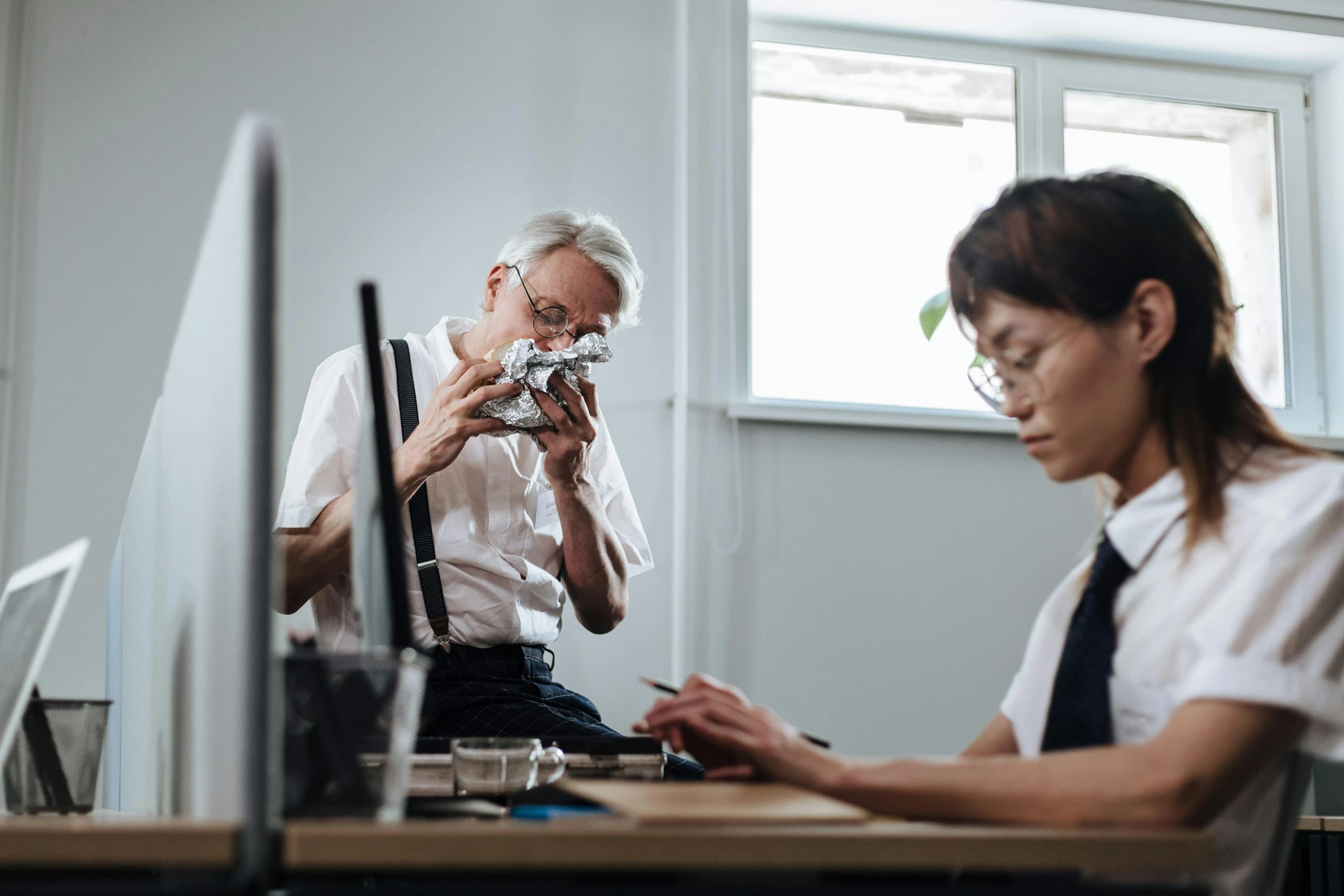 two people at their desk working on some type of computer