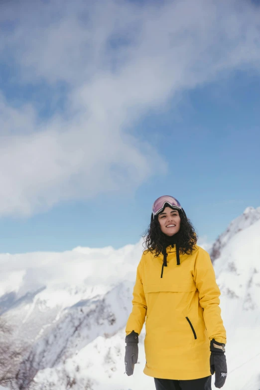 a girl in yellow jacket standing on top of a snowboard