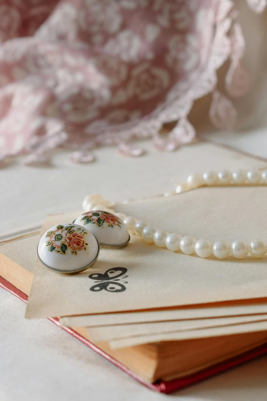 a stack of notebooks with flowers and a bunch of pearls