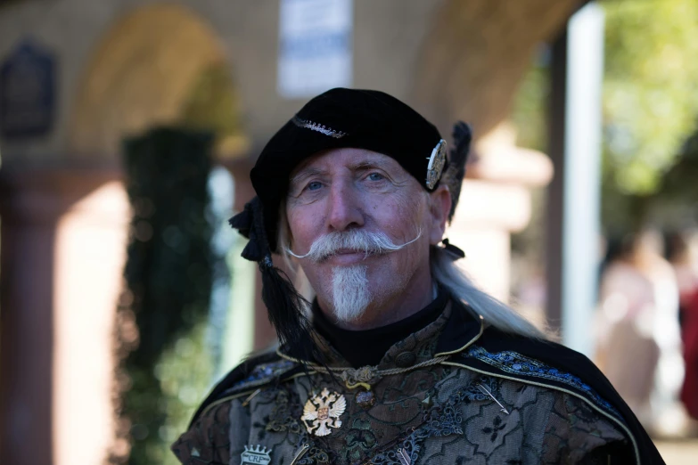 an older man with white beard wearing a hat and a suit