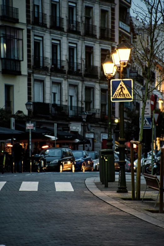 a cross walk on the corner in front of a bunch of parked cars