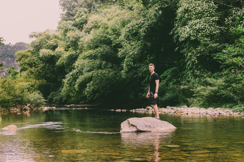 a man standing on a rock in the middle of a river