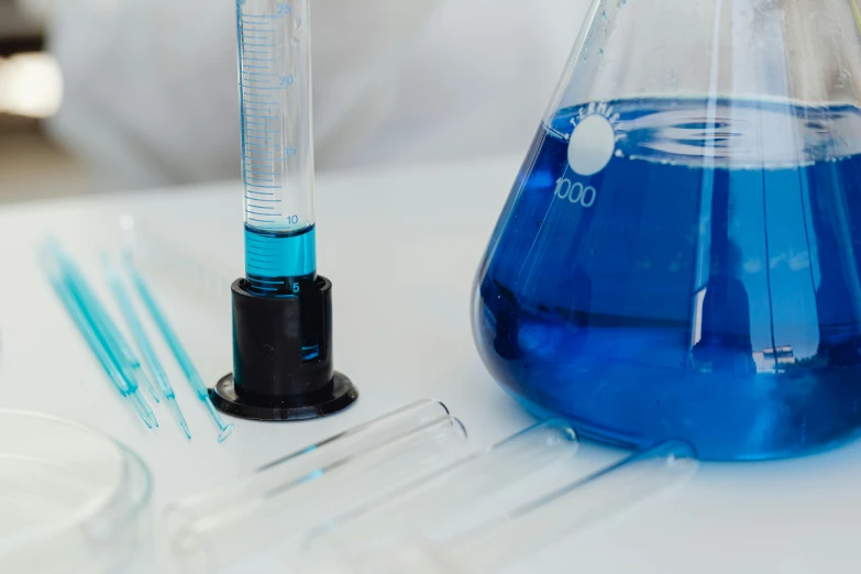 blue liquid next to some empty glassware with blue tooth picks