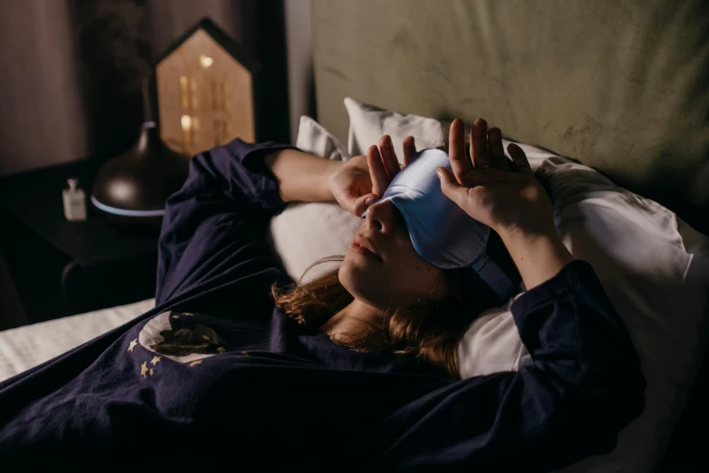 a woman laying on a bed and drinking from a cup