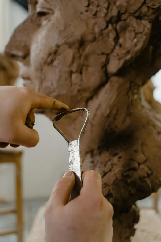 someone holding a small pair of scissors in front of a sculpture