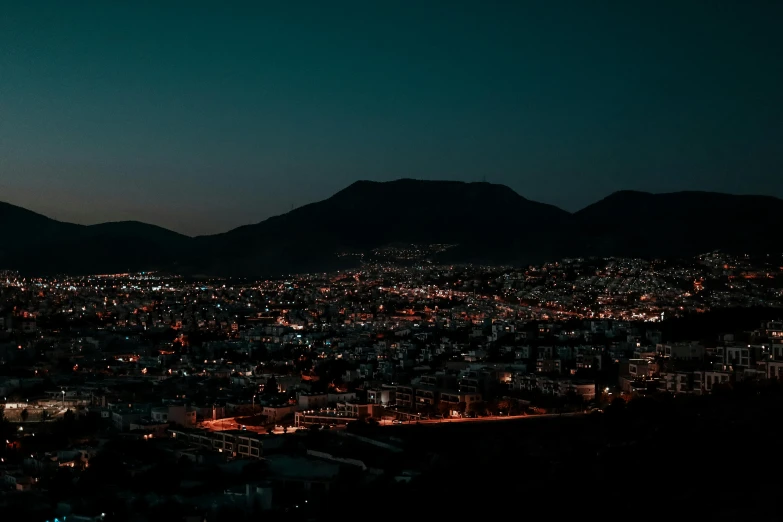 the city lights at night with some mountains in the background