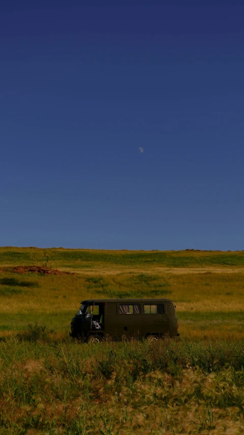 a small truck in a grassy field with a sky background