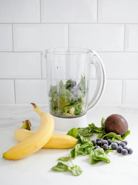 a blender and an arrangement of fruits and vegetables on a counter