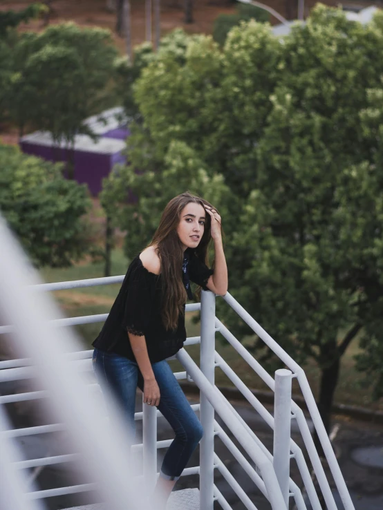 a girl standing on top of a white railing in a park