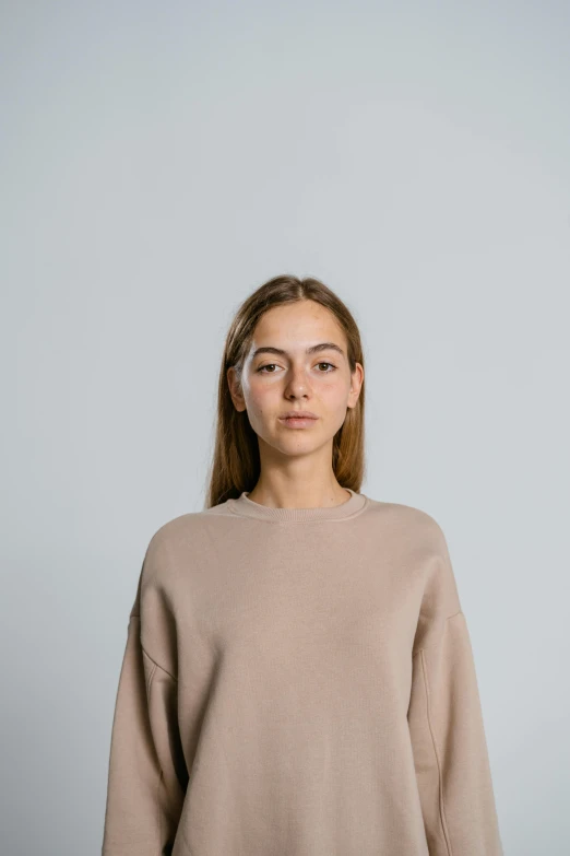 a girl poses for a po in a beige jumper