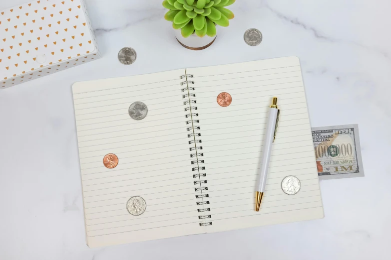 an empty notebook is surrounded by notes and coins