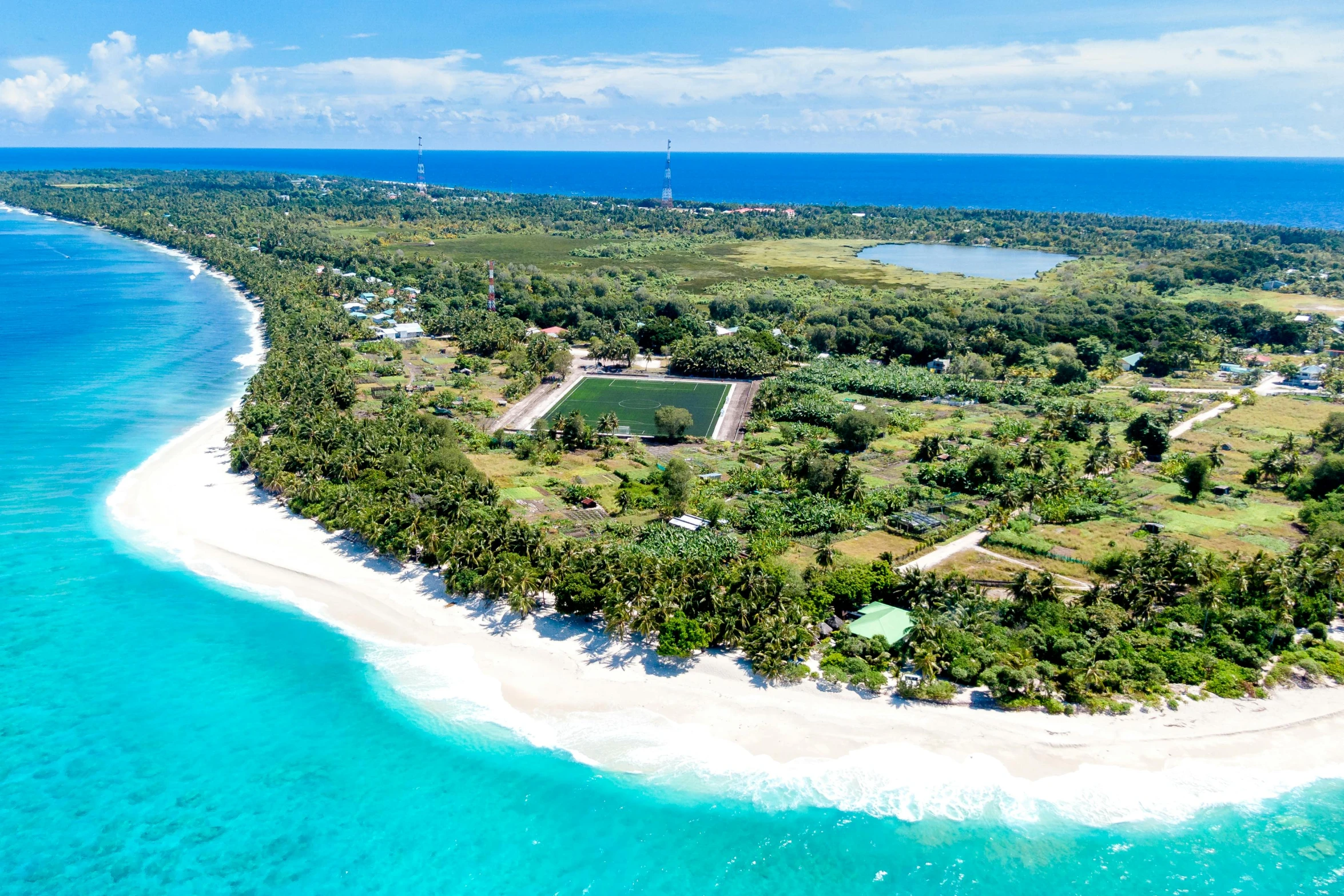 a white sand beach and green trees near an ocean