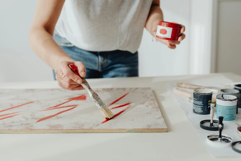 a woman using a brush to paint a canvas