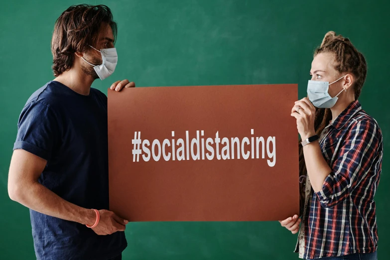 two people with masks hold a sign that reads socializing