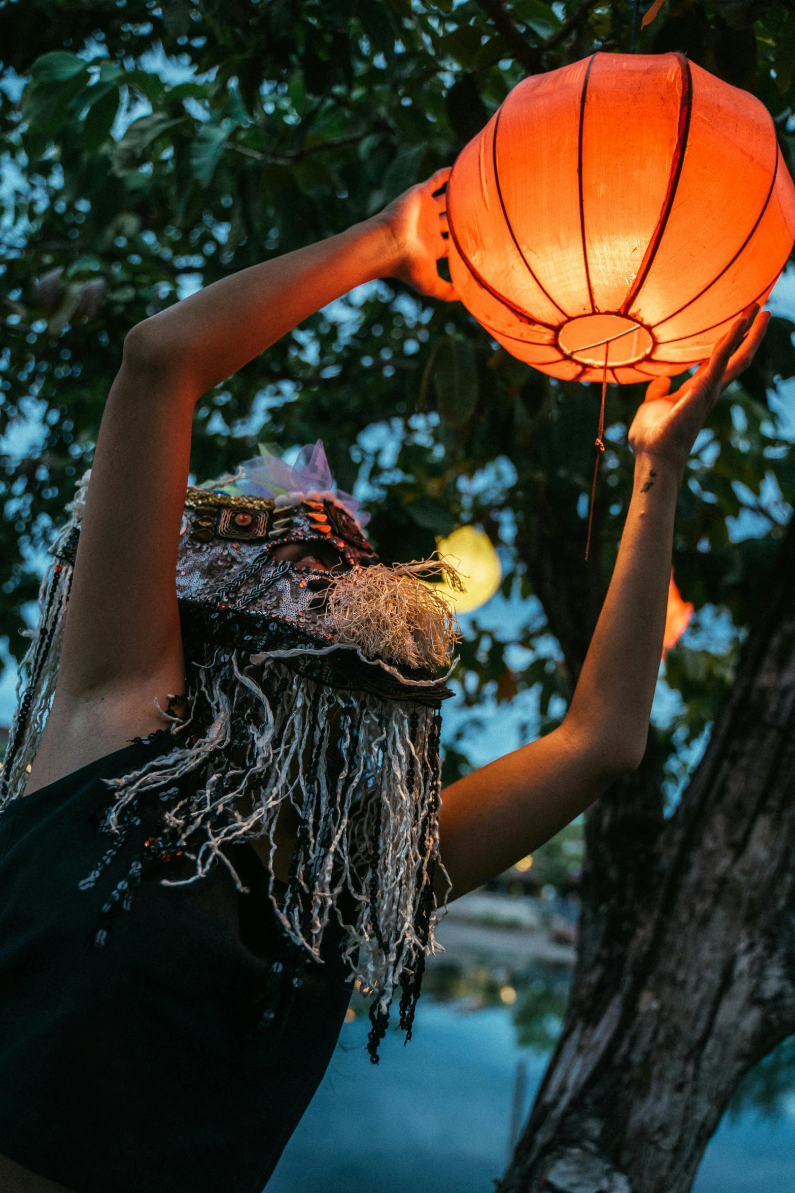 the woman is holding up a bright orange lantern