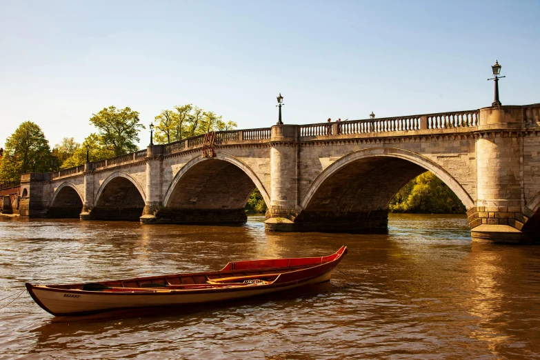 a boat on a river in front of a stone bridge