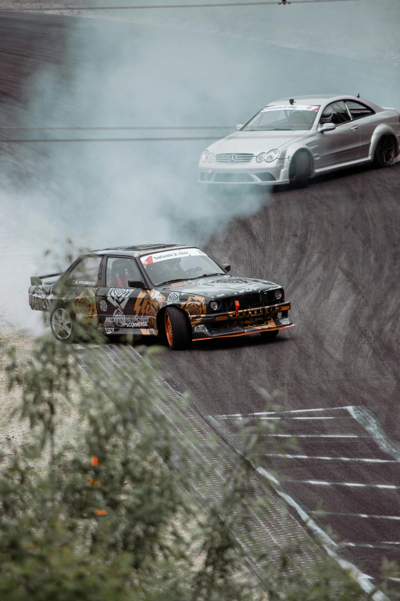 two cars with different colored tires driving around in the dirt