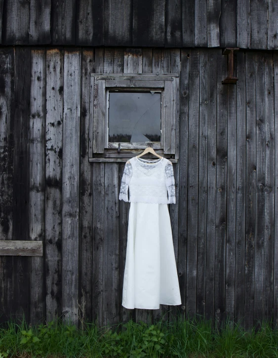 a dress on a clothesline against an old barn wall