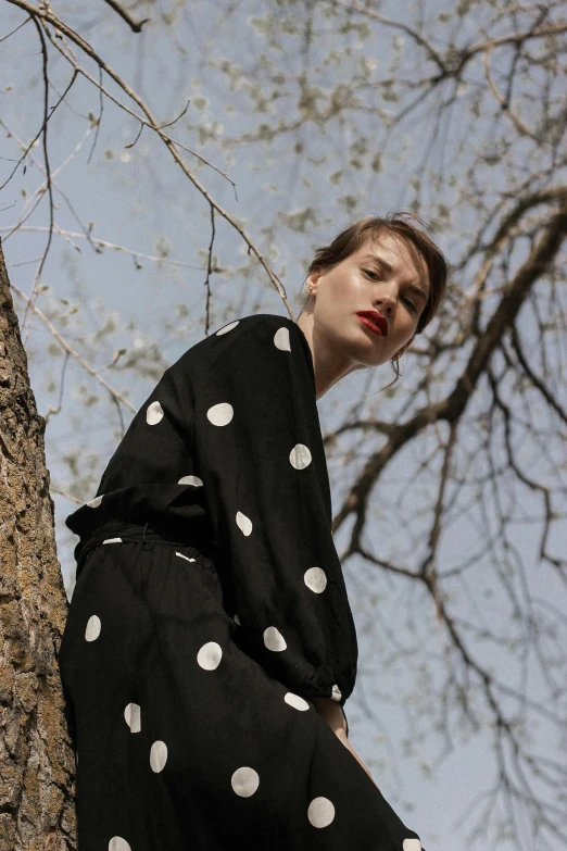 a woman in black and white polka dots standing on a tree