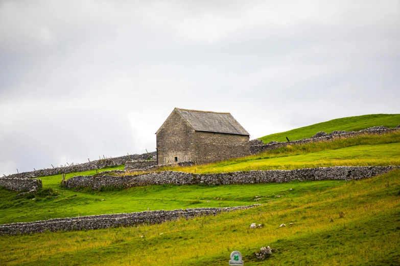 an old house on a hill next to a sheep grazing