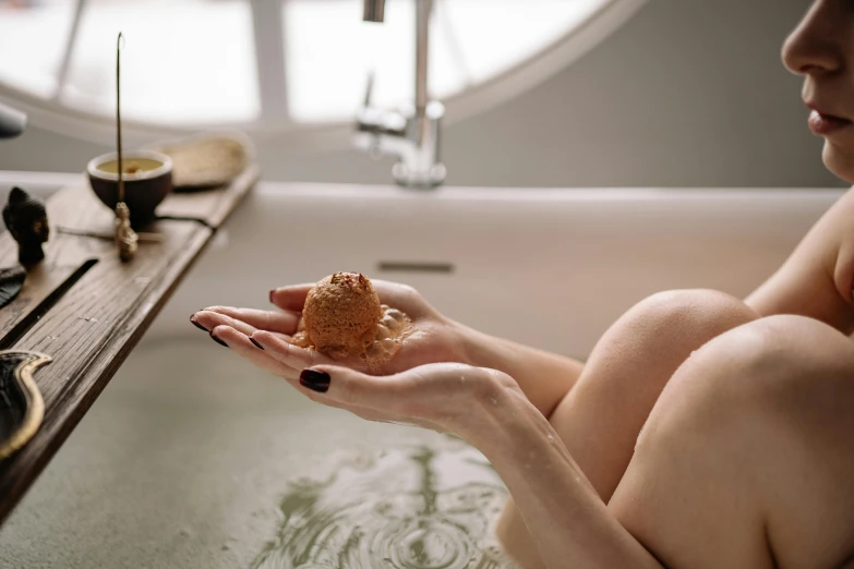 woman sitting in bathtub holding out a peanut brittler